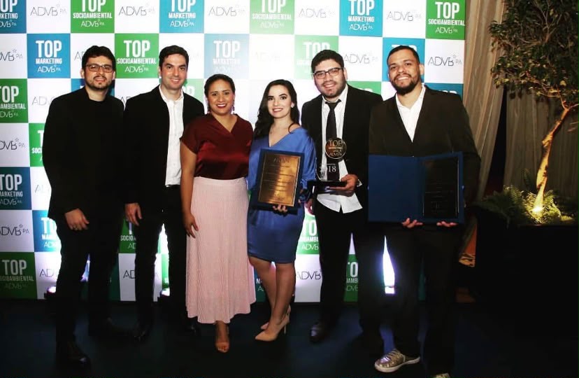 Equipe premiada posando com troféus e certificados Top Marketing 2018